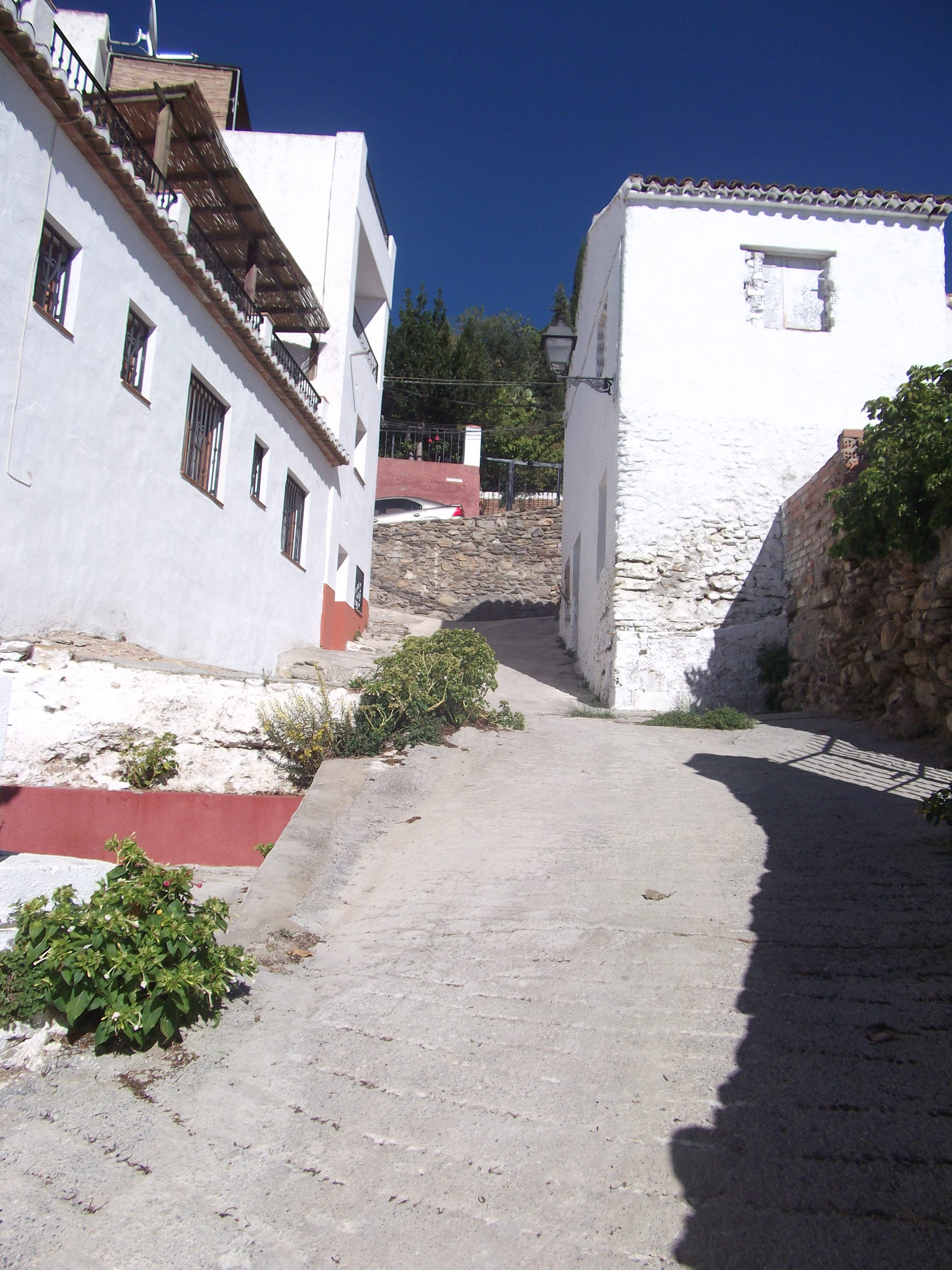 Calle estrecha y encalada del casco antiguo, en cuesta